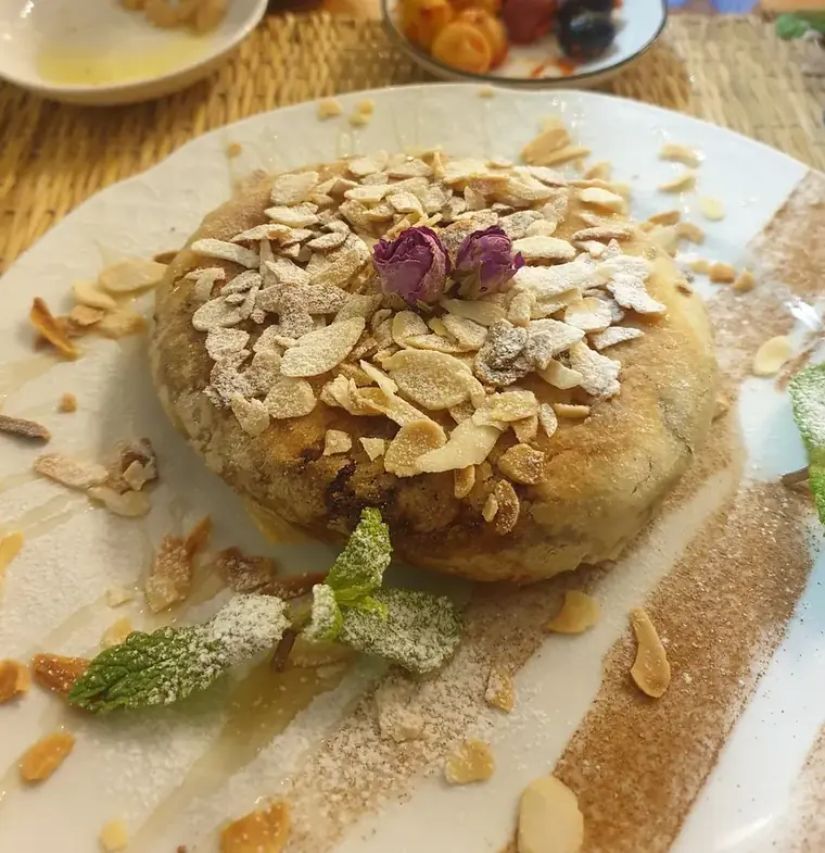 Pastilla aux amandes saupoudrée de cannelle et sucre glace, boutons de rose.