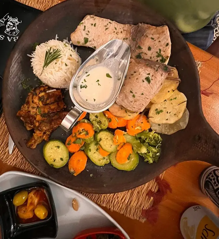 Poisson vapeur, riz, légumes sautés et sauce, sur plat en bois.